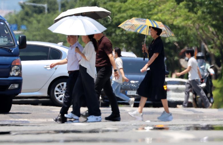 전국 대부분 지역에 폭염 특보가 발효된 3일 광주 서구 치평동에서 시민들이 강렬한 햇빛에 달구어져 아지랑이가 피어오르는 도로를 걷고 있다.[연합]