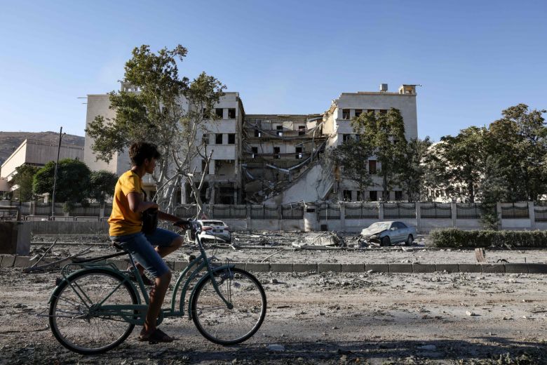 시리아 수도 다마스커스에 거주하는 한 청년이 이스라엘 공습으로 부서진 시리아 국방부 청사를 지나고 있다. [AFP]