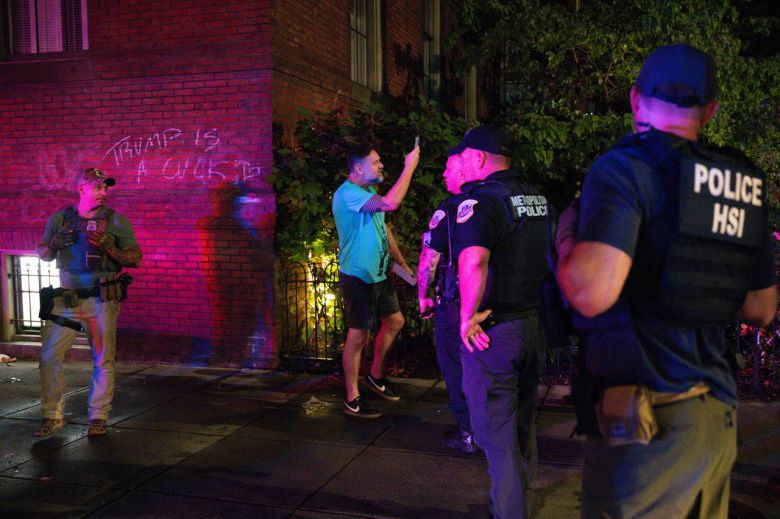 17일 워싱턴 DC 14번가의 한 식당에서 재산 훼손 혐의로 한 개인을 체포하는 과정에서, DC 경찰청(MPD) 소속 경찰관이 구경꾼에게 물러서라고 요구하고 있다. [AFP]