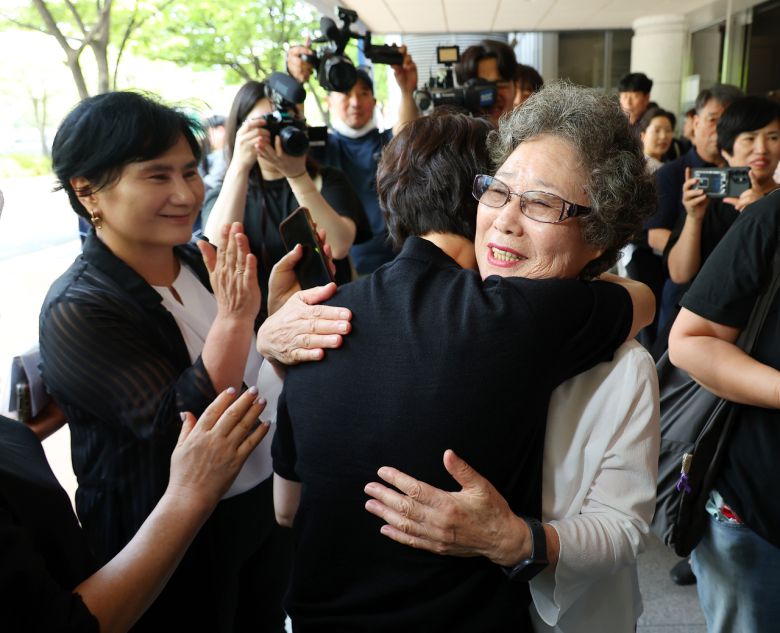 61년 전 자신을 성폭행하려던 남성의 혀를 깨물어 중상해 혐의 유죄 판결을 받았던 최말자(78)씨가 지난 7월 23일 부산지법에서 열린 재심 첫 공판을 마치고 법정을 나서며 변호인과 여성단체와 포옹하고 있다. [연합]