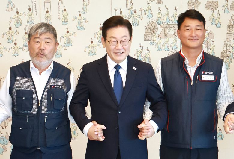 이재명 대통령이 4일 서울 용산 대통령실 청사에서 열린 양대노총 위원장과의 오찬 간담회에 참석해 김동명 한국노총 위원장(왼쪽), 양경수 민주노총 위원장과 기념촬영을 하며 손을 잡고 있다. [연합]