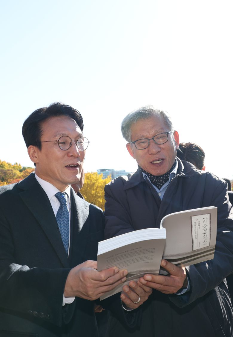 김민석 국무총리가 10일 서울시의 종묘 앞 고층건물 허용과 관련해 허민 국가유산청장, 유홍준 국립중앙박물관장 등과 함께 종로구 종묘를 방문, 유 관장의 저서인 ‘나의 문화유산답사기’를 보며 역사적 의미를 확인하고 있다. [연합]