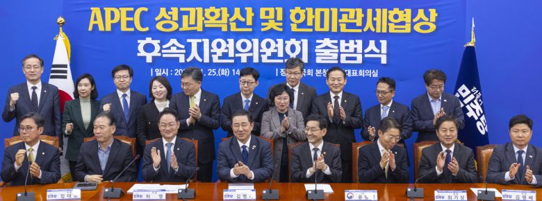 25일 국회에서 열린 아시아태평양경제협력체(APEC) 성과확산 및 한미관세협상 후속지원위원회 1차 회의에서 더불어민주당 의원들과 정부 관계자들이 기념 촬영을 하며 박수치고 있다. [연합]