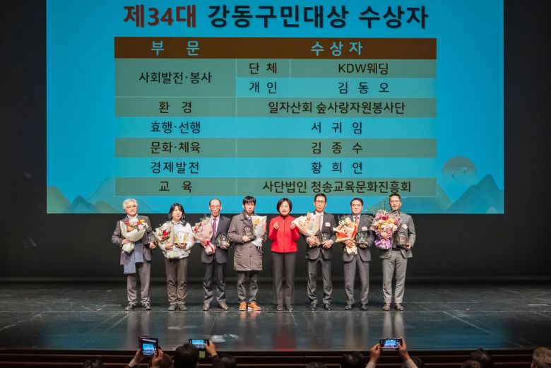 무대 위에 제34대 강동구민대상 수상자들과 이들이 꽃다발을 들고 환하게 웃고 있는 사진이다. 무대 배경에는 수상 부문과 수상자 이름이 적혀 있다.