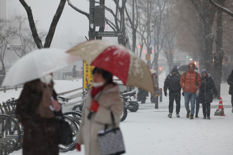 지난 12일 서울 종로구 종각역 인근에서 시민들이 눈을 맞으며 이동하고 있다. [연합]