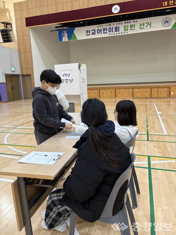 전교 임원 선거에서 학생이 투표용지를 전달하며 직접 선거 절차에 참여하고 있다