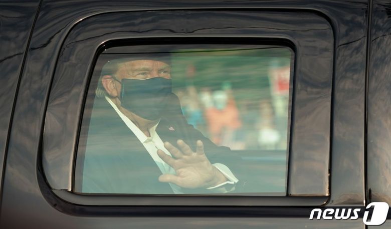 도널드 트럼프 미국 대통령이 4일(현지시간) 코로나19로 입원 중인 메릴랜드주 베세스다에 있는 월터 리드 군 병원 밖으로 차를 타고 나와 지지자들 앞을 지나면서 손을 흔들고 있다. © AFP=뉴스1 © News1 우동명 기자