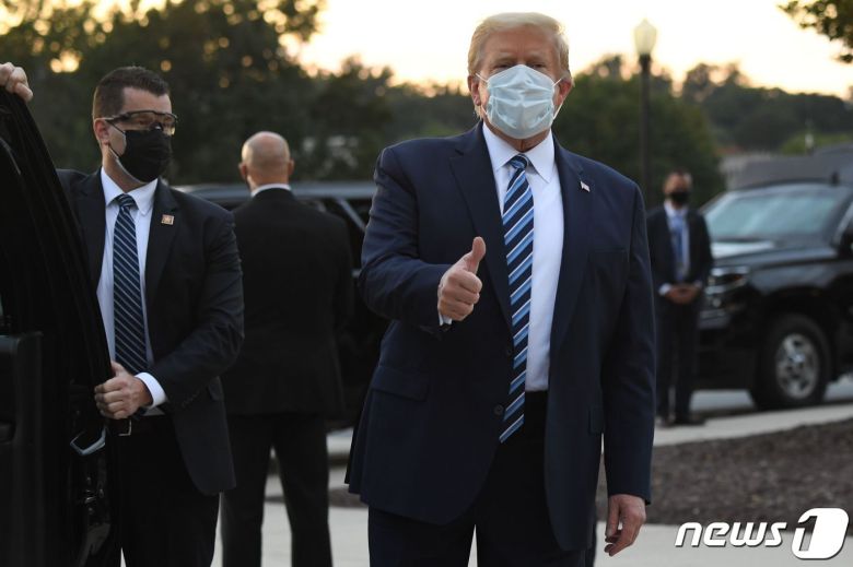 도널드 트럼프 미국 대통령이 5일(현지시간) 오후 코로나19 치료를 위해 입원 중이던 월터 리드 군병원에서 조기 퇴원한 뒤 차량으로 이동하면서 취재진을 향해 오른손 엄지손가락을 들어보이고 있다. © AFP=뉴스1