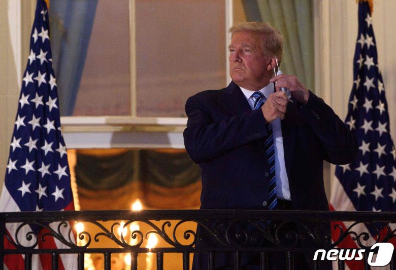 도널드 트럼프 미국 대통령이 5일(현지시간) 오후 백악관에 복귀한 뒤 쓰고 있던 마스크를 벗고 있다. © AFP=뉴스1