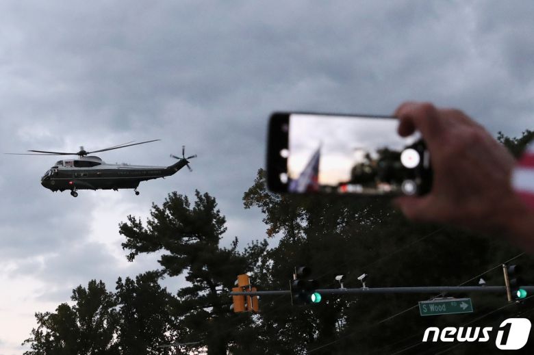 도널드 트럼프 미국 대통령이 탑승한 전용 헬기(마린원)이 5일(현지시간) 오후 월터 리드 군병원을 떠나 백악관으로 향하는 모습을 지지자들이 휴대전화 카메라로 촬영하고 있다. © 로이터=뉴스1