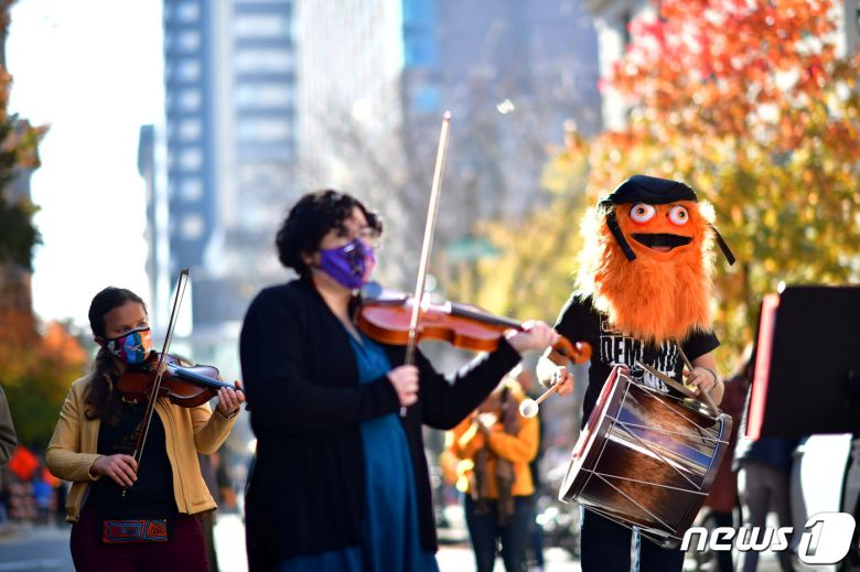 바이올린을 연주하며 즐겁게 행진하는 바이든 후보 지지자들 © 로이터=뉴스1
