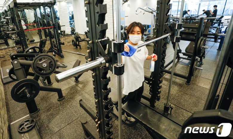 지난달 7일 오픈 시위 중인 서울시내 헬스장에서 트레이너가 기구를 소독하고 있다. 정부는 이날 학원, 태권도장과 동일하게 아동 학습 목적을 가진 실내체육시설에 대해 9인 이하 교습을 허용하기로 했으나 헬스장은 포함되지 않아 형평성 논란이 불거졌다. 2021.1.7/뉴스1 © News1 안은나 기자