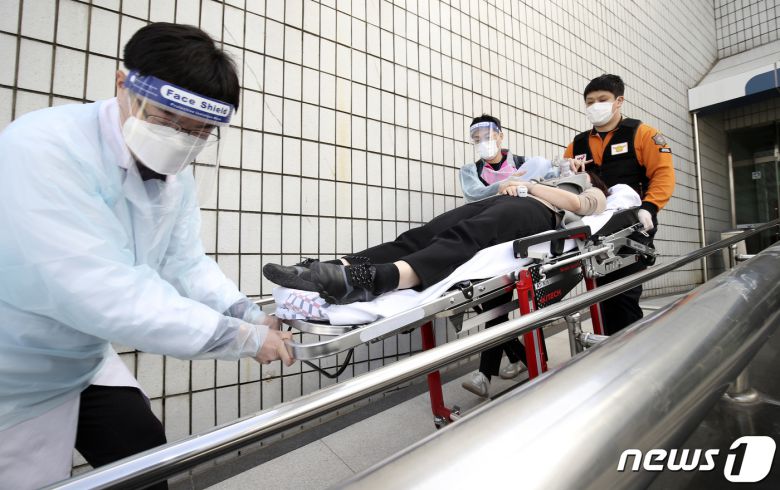 18일 오전 울산 중구 동천체육관에 마련된 코로나19 예방접종센터에서 지역 예방접종센터 모의훈련이 실시된 가운데 의료진과 구급대원이 이상반응 발생 접종대상자를 구급차로 이송하고 있다. 2021.3.18 /뉴스1 © News1 윤일지 기자