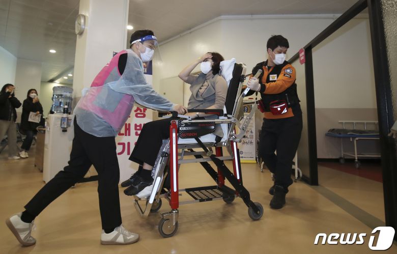 18일 오전 울산 중구 동천체육관에 마련된 코로나19 예방접종센터에서 지역 예방접종센터 모의훈련이 실시된 가운데 의료진과 구급대원이 이상반응 발생 접종대상자를 응급처치실로 이송하고 있다. 2021.3.18 /뉴스1 © News1 윤일지 기자