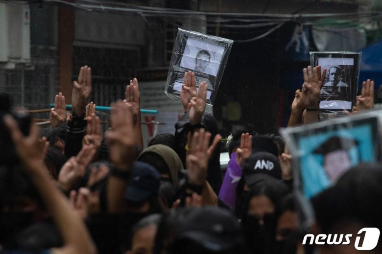 5일(현지시간) 미얀마 양곤에서 군부 쿠데타를 규탄하는 시위대가 시위 중 숨진 시민의 사진을 들고 세 손가락 경례를 하고 있다. © AFP=뉴스1 © News1 우동명 기자