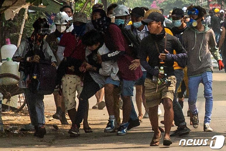 29일(현지시간) 미얀마 양곤에서 군사 쿠데타에 반대하는 시위대가 군경과 충돌 중 부상을 당한 동료를 옮기고 있다. © AFP=뉴스1 © News1 우동명 기자