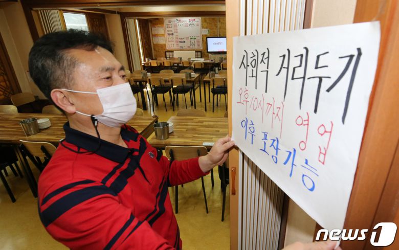 대전지역에서 학원 발 신종 코로나바이러스 감염증 N차 감염 확산으로 사회적 거리두기가 2단계로 격상된 8일 오후 대전 서구에 위치한 식당에서 주인이 10시 이후 영업제한을 알리는 안내문을 붙이고 있다. 2021.4.8/뉴스1 © News1 김기태 기자