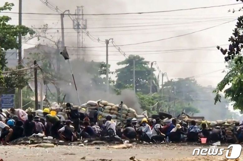 29일(현지시간) 미얀마 양곤에서 군사 쿠데타에 반대하는 시위대가 군경과 충돌 중 바리케이드 뒤로 피하고 있다. © AFP=뉴스1 © News1 우동명 기자