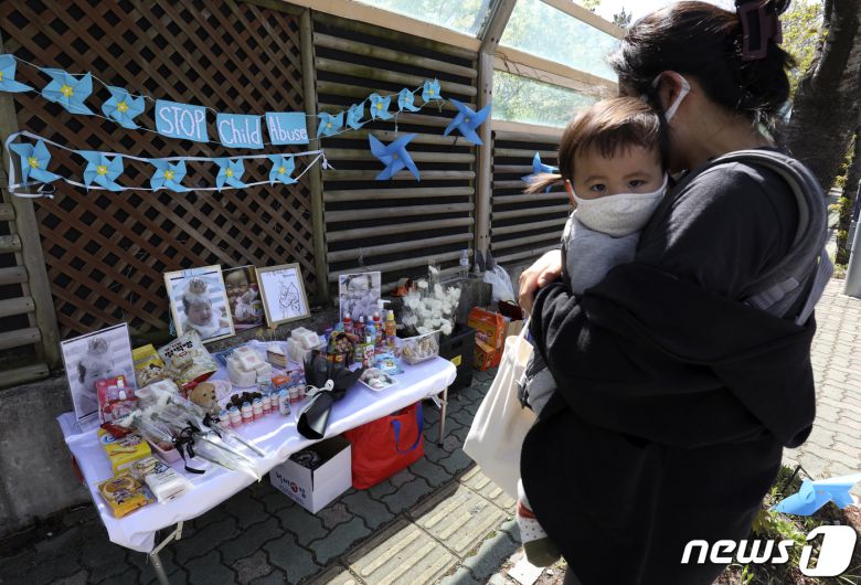 14일 오후 아기를 안은 한 시민이 울산지방법원 앞에 마련된 정인이의 제사상을 바라보고 있다. 2021.4.14/뉴스1 © News1 윤일지 기자