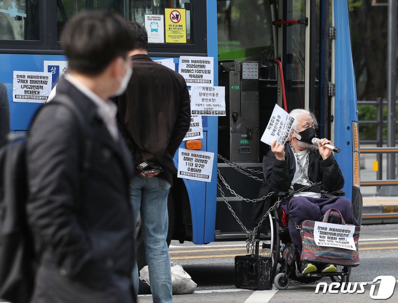 박경석 전국장애인차별철폐연대 이사장이 6일 오전 서울 종로구 종각역 인근 버스전용차로에서 운행 중인 시내버스를 점거한 후 저상버스 100% 도입을 촉구하고 있다. 2021.4.6/뉴스1 © News1 김진환 기자