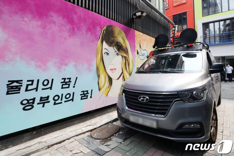 29일 서울 종로구의 한 서점 벽면에 그려진 윤석열 전 검찰총장의 배우자 김건희 씨를 비방하는 내용의 벽화를 보수단체 관계자들이 차량으로 막아서고 있다. 2021.7.29/뉴스1 © News1 민경석 기자