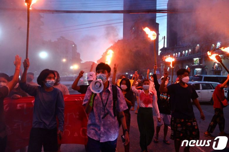 미얀마 양곤서 열린 군사 쿠데타 반대 시위에서 시위대가 횃불을 든 채 세 손가락 경례를 하고 있다. © AFP=뉴스1 © News1 서한샘 기자