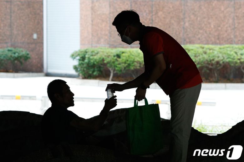 김영택 서울특별시립 구세군 브릿지 종합지원센터 기획상담과 과장이 전국에 폭염특보가 발효된 3일 오후 서울 중구 서소문 고가 아래에서 노숙인에게 물과 마스크를 나눠주고 있다.  2021.8.3/뉴스1 © News1 안은나 기자