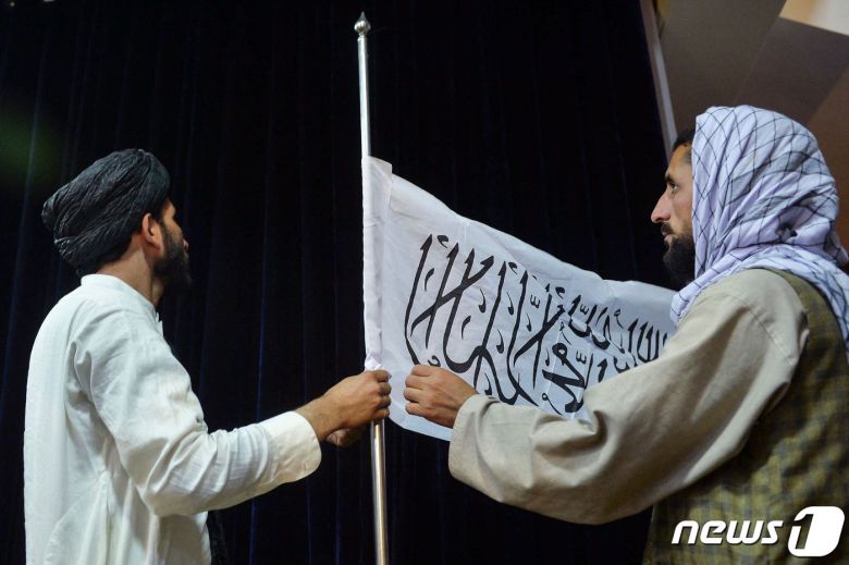 17일(현지시간) 탈레반이 아프가니스탄 정권을 재장악한 뒤 자비훌라 무자히드 탈레반 대변인이 첫 기자회견에 도착하기 앞서 아프간인이 탈레반기를 달고 있다. © AFP=뉴스1 © News1 우동명 기자