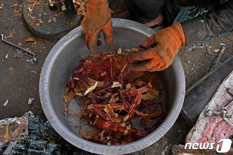 아프가니스탄 수도 카불 정크야드에서 한 남성이 재생에너지 물품으로부터 구리 성분을 모으고 있다. 2021.06.12 © AFP=뉴스1