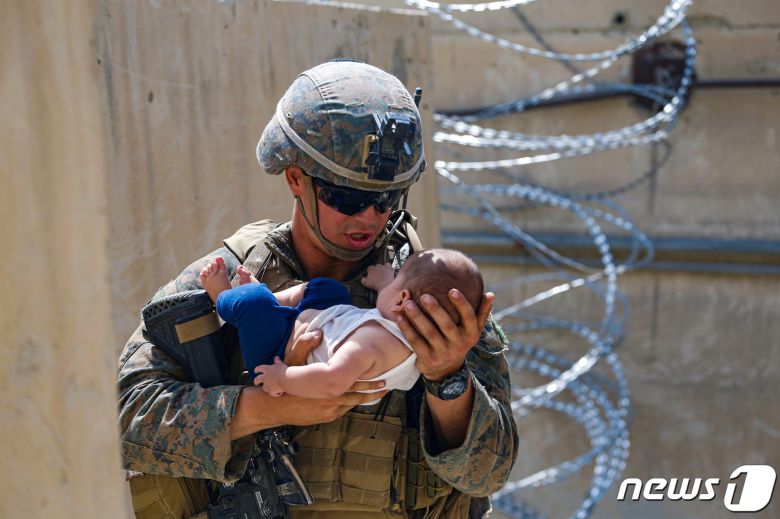 21일(현지시간) 탈레반이 장악한 아프가니스탄의 카불 공항에서 미군이 아프간 아기를 안고 달래며 엄마를 기다리고 있다. © 로이터=뉴스1 © News1 우동명 기자