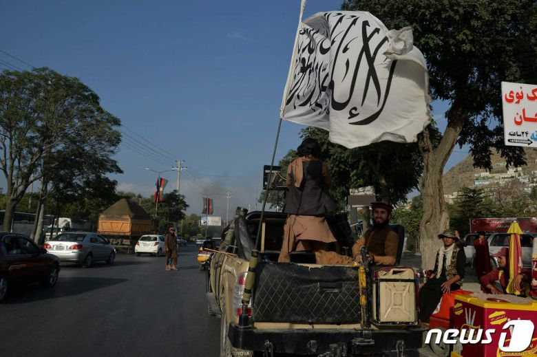 22일(현지시간) 탈레반들이 자신들의 깃발을 들고 카불 도심 거리를 거닐고 있다. © AFP=뉴스1 © News1 구진욱 기자