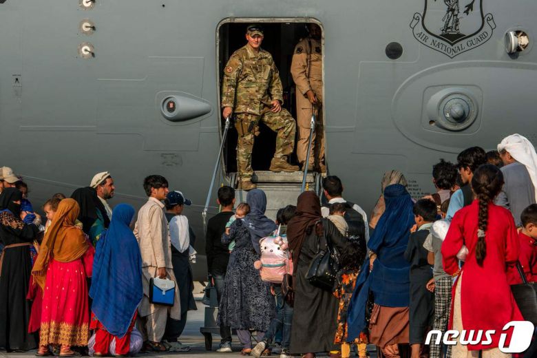 카타르 수도 도하의 우데이드 공군기지에서 피난민들이 22일(현지시간) 미 군수송기 C-17 탑승을 위해 줄 서 있다. 2021.08.22 © AFP=뉴스1