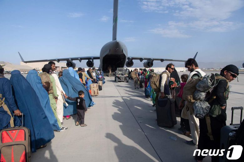 25일 미국에 조력한 아프가니스탄인들이 카불 하미드 카르자이 국제공항에서 미군 C-17 수송기에 탑승할 준비를 하고 있다. © AFP=뉴스1