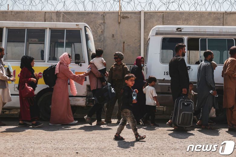 22일(현지시간) 카불에서 아프가니스탄 난민들이 하미다 카르자이 국제공항에서 환승 버스를 기다리고 있다. © AFP=뉴스1 © News1 구진욱 기자