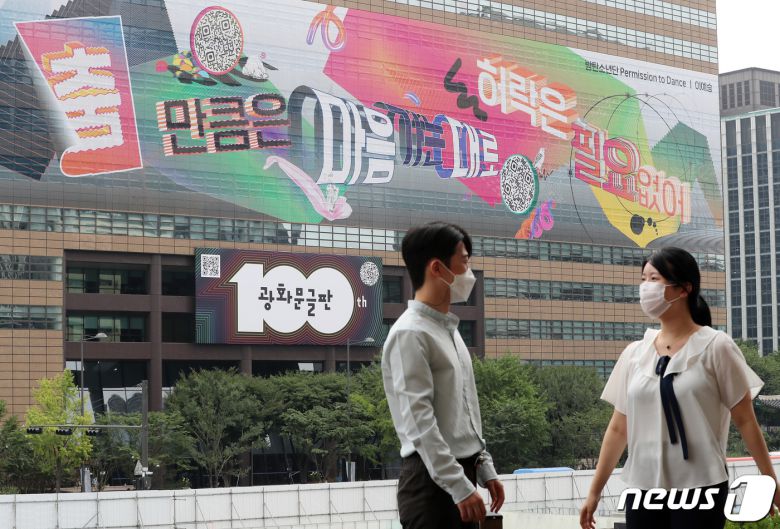 30일 오전 서울 종로구 교보빌딩에 100번째 광화문글판 '춤 만큼은 마음 가는 대로, 허락은 필요 없어'를 바라보며 시민들이 대화를 나누고 있다. 글로벌 아티스트 방탄소년단(BTS)가 100번째 광화문글판을 위해 문안 제작에 참여한 이번 글판은 코로나 펜데믹으로 제약이 늘고 고단한 하루 속에서도 허락받지 않고 자유로움을 느낄 수 있는 것을 찾자는 메시지를 담았다. 2021.8.30/뉴스1 © News1 박세연 기자