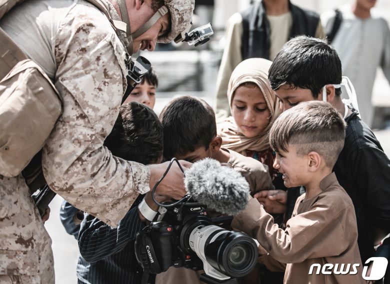 아프가니스탄 하미드 카르자이 국제공항에서 2021년 8월 22일(현지시간) 대피를 기다리는 아이들이 미군의 비디오 카메라를 보며 해맑게 웃고 있다. © 로이터=뉴스1 © News1 최서윤 기자