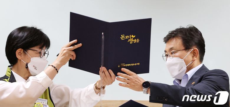 보건복지부와 전국보건의료산업노동조합(보건의료노조)의 노정실무교섭이 극적 타결된 2일 오전 서울 영등포구 의료기관평가인증원에서 권덕철 보건복지부 장관(오른쪽)과 나순자 보건의료노조위원장이 서명한 합의서를 교환하고 있다. 2021.9.2/뉴스1 © News1 조태형 기자