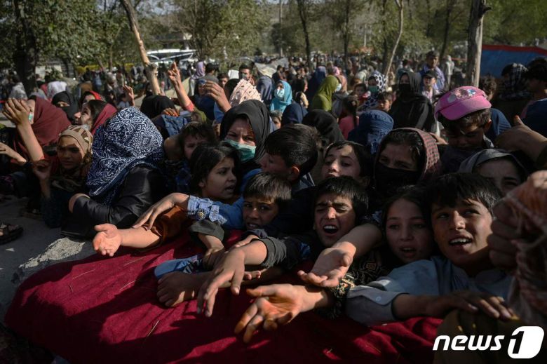 9일(현지시간) 아프가니스탄 정부와 탈레반과 전쟁이 벌어지고 있는 가운데 수도 카불에서 전쟁 지역에서 피난온 어린이들이 구호 식량을 얻기 위해 손길을 내밀고 있다. 2021.08.09 © AFP=뉴스1
