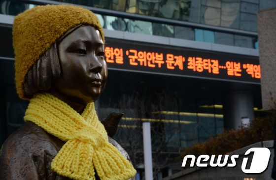 한일간 위안부 문제가 타결된 28일 오후 서울 종로구 일본대사관 앞에 설치된 소녀상 뒤로 타결 관련 뉴스가 속보로 전해지고 있다. 한일 양국은 이날 오후 서울 도렴동 외교부 청사에서 윤병세 외교부 장관과 일본의 기시다 외무상 간 외교장관회담을 갖고 일본 정부의 책임 통감과 내각총리의 사죄 표명을 골자로 한 위안부 문제 해결방안에 합의했다.2015.12.28/뉴스1 © News1 허경 기자