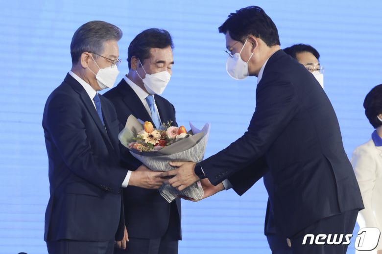 더불어민주당 제20대 대통령선거 후보에 선출된 이재명 경기지사가 10일 오후 서울 송파구 올림픽공원 SK올림픽핸드볼경기장에서 열린 서울 지역 경선 및 3차 국민선거인단 투표에서 1위를 차지한 뒤 송영길 대표로부터 축하 꽃다발을 받고 있다. 2021.10.10/뉴스1 © News1 국회사진취재단