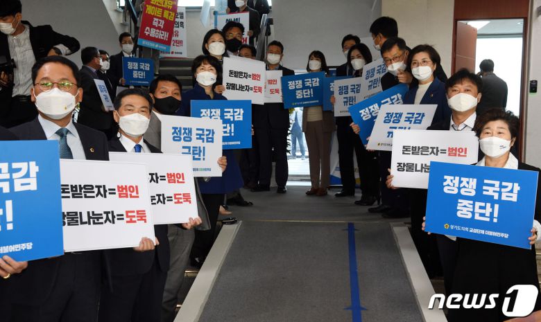 국회 국토교통위원회의 경기도에 대한 국정감사가 열린 20일 오전 수원시 경기도청 국정감사장 입구에서 더불어민주당 소속 경기도의회 의원들이 '대장동 개발 특혜 의혹' 관련 팻말을 들고 있다. 2021.10.20/뉴스1 © News1 국회사진취재단