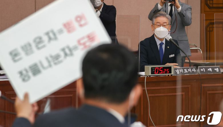 이재명 경기도지사가 20일 경기도 수원시 팔달구 경기도청에서 열린 국회 국토교통위원회의 경기도에 대한 국정감사에서 대장동 관련 피켓을 든 박정민 국민의힘 의원을 바라보고 있다. 2021.10.20/뉴스1 © News1 국회사진취재단