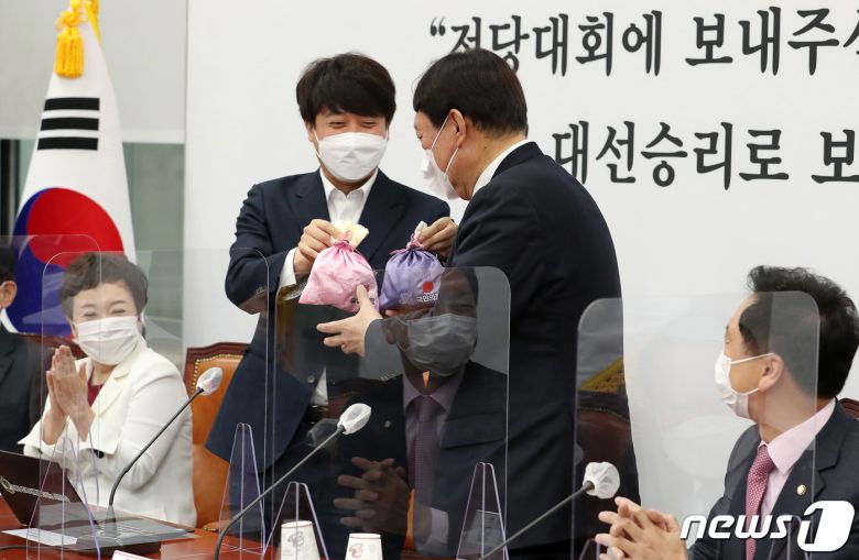 이준석 국민의힘 대표(왼쪽)가 8일 오전 서울 여의도 국회에서 열린 최고위원회의에서 윤석열 대선후보에게 비단주머니를 전달하고 있다. 2021.11.8/뉴스1 © News1 이동해 기자