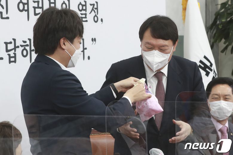 이준석 국민의힘 대표(왼쪽)가 8일 오전 서울 여의도 국회에서 열린 최고위원회의에서 윤석열 대선후보에게 비단주머니를 전달하고 있다. 2021.11.8/뉴스1 © News1 이동해 기자