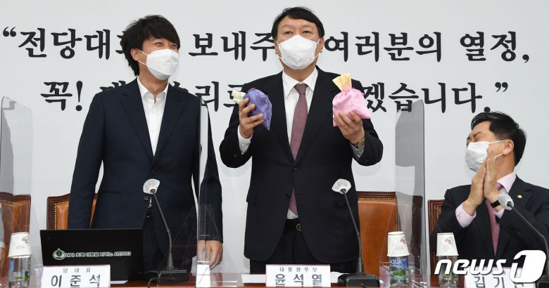 윤석열 국민의힘 대선후보(왼쪽 두 번째)가 지난 8일 오전 서울 여의도 국회에서 열린 최고위원회의에서 이준석 대표에게 비단주머니를 받은 후 발언하고 있다. 2021.11.8/뉴스1 © News1 이동해 기자