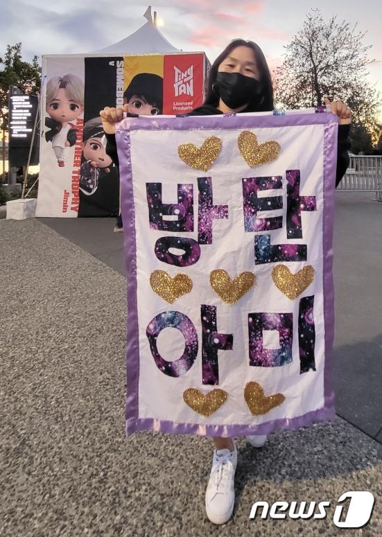 그룹 방탄소년단(BTS)가 2년만에 미국에서 대면콘서트를 가졌다. 27일 오후 로스앤젤레스 소파이(SO-FI) 스타디움에서 'BTS 퍼미션 투 댄스 온 스테이지 인 LA'(BTS PERMISSION TO DANCE ON STAGE in LA)의 첫날 공연을 찾은 한 팬이 공연장에 들어가기 전 응원 문구를 들어보이며 사진을 찍고 있다. 2021.11.28/뉴스1 © News1 고승아 기자