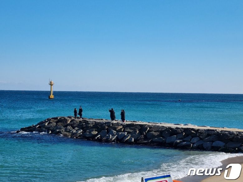 거리두기 강화 첫 주말인 19일 드라마 '도깨비' 촬영지로 유명한 강릉 영진해변에서 몇몇 방문객들이 사진을 찍고 있다.2021.12.19/뉴스1 윤왕근 기자