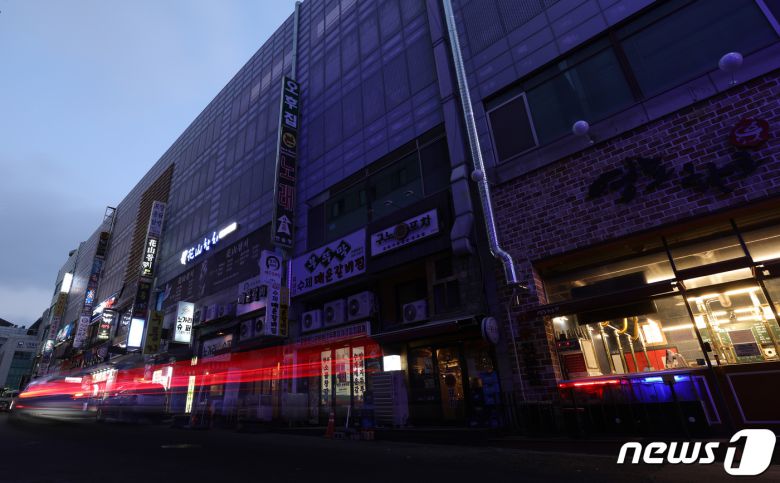 27일 오후 경기도 수원시 영통구의 한 먹자골목에서 상인들이 간판을 소등하고 영업을 하고 있다. 2021.12.27/뉴스1 © News1 김영운 기자