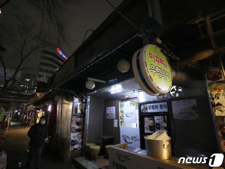 코로나피해자영업총연합(코자총)이 정부의 방역지침 강화에 항의해 간판과 입간판을 끄는 소등 시위를 시작한 27일 저녁 서울 도심의 먹자골목에서 상인들이 소등 시위에 참여하고 있다. 코자총 소속 자영업자들은 오늘과 내일 이틀간 오후 5시부터 4시간 동안 건물 노출 간판과 입간판을 소등하고 영업하는 시위를 진행한다고 밝혔다. 2021.12.27/뉴스1 © News1 박정호 기자