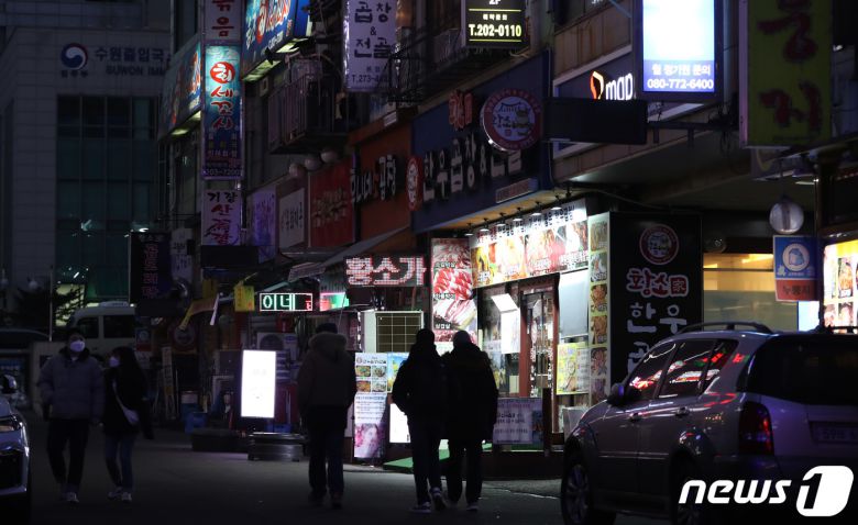 27일 오후 경기도 수원시 영통구의 한 먹자골목에서 상인들이 간판을 소등하고 영업을 하고 있다. 2021.12.27/뉴스1 © News1 김영운 기자